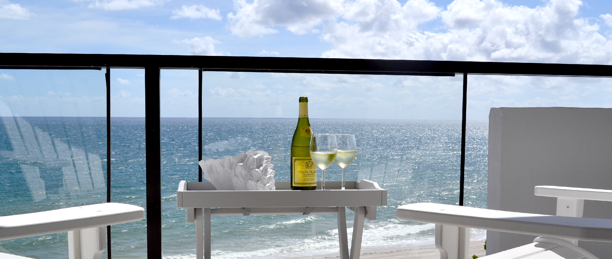 Terrasse face à l'océan avec un plateau et deux verres de vin blanc