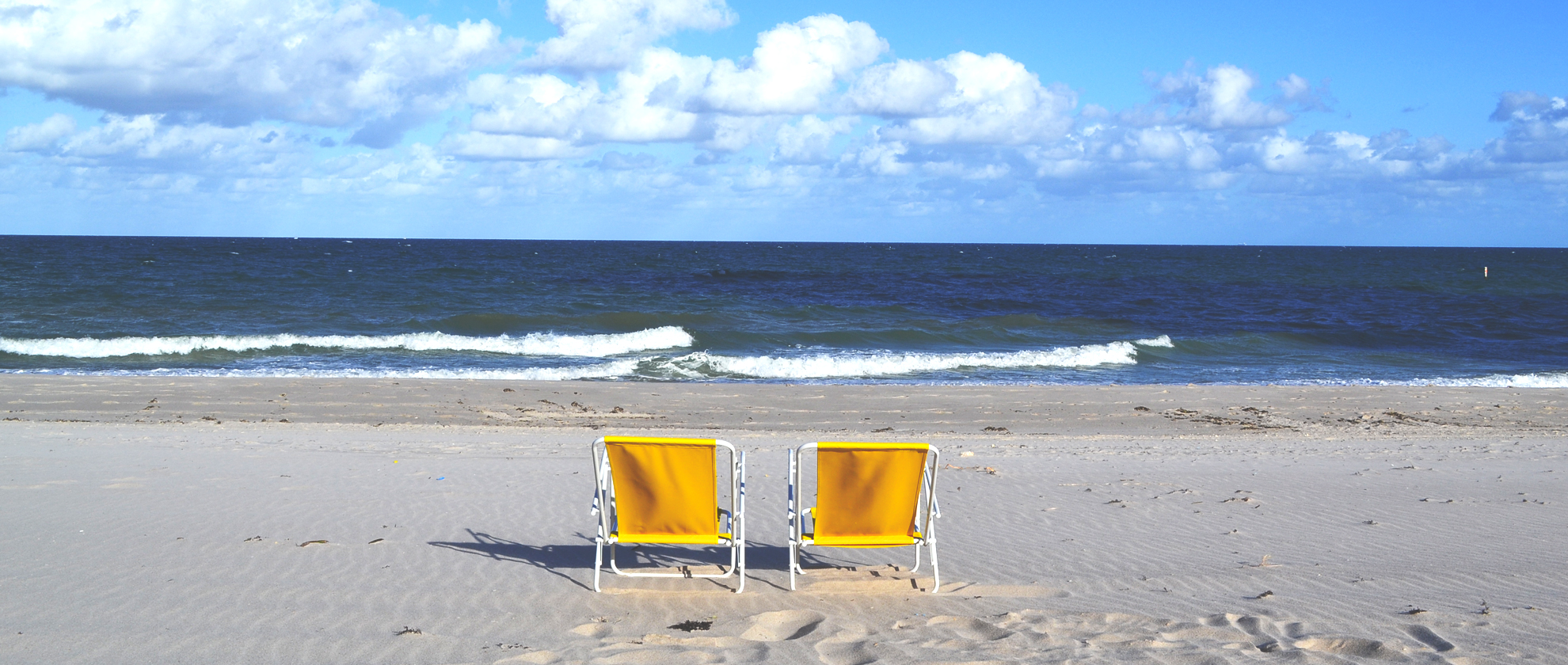 Deux transats jaunes face à l'océan sur la plage de Lauderdale by the Sea